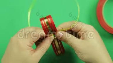 女人`双手用绿色<strong>胶带</strong>绑起<strong>一块</strong>空白的红丝带，做礼物蝴蝶结。 绿色背景